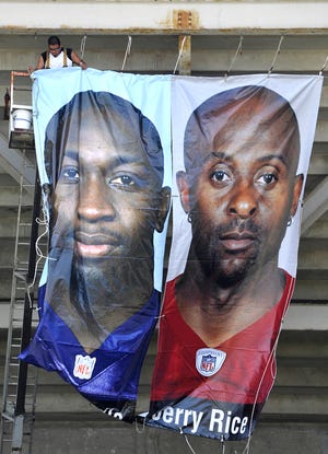 Alonzo Peche III of Canton Sign Company installs a banner of John Randle and Jerry Rice, members of The Pro Football Hall of Fame's Class of 2010 on Fawcett Stadium.