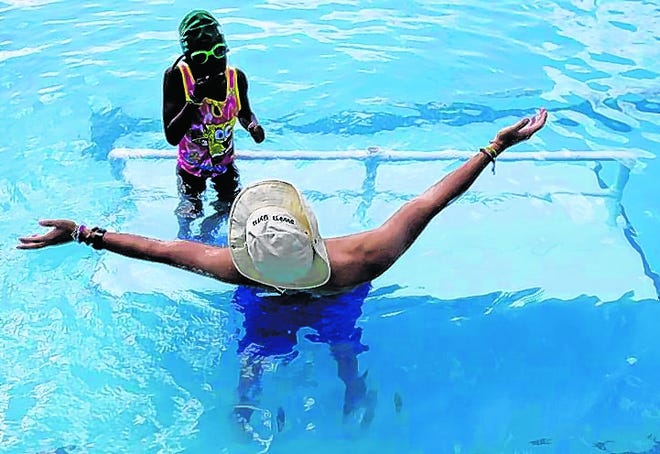 Swimming instructor Juan Sebastian Barreneche encourages Queen Epps, 6, to jump off the ledge during a swimming class at Swim Gym in Key Biscayne.