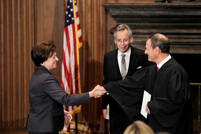 Elena Kagan, left, is congratulated by Chief Justice John Roberts, right, after becoming the Supreme Court's newest member Saturday, Aug. 7, 2010, at the Supreme Court Building in Washington. The Bible was held by Jeffrey Minear, center, counselor to the chief justice. Kagan, 50, who replaces retired Justice John Paul Stevens, becomes the fourth woman to sit on the high court and is the first Supreme Court justice in nearly four decades with no previous experience as a judge. (AP Photo/J. Scott Applewhite)