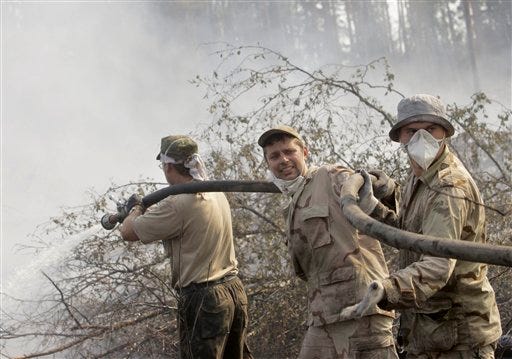 Alexander Babayev, center, one of volunteers enlisted through a social network to help Russian firefighters extinguish a forest fire near the village of Plotava, 80 km (49 miles) east of Moscow, Thursday, Aug. 5, 2010. Temperatures up to 100 degrees Fahrenheit (38 Celsius) have exacerbated forest and peat bog fires across Russia's central and western regions, destroying close to 2,000 homes. Officials have suggested the 10,000 firefighters battling the blazes aren't enough to go around.(AP Photo/Sergey Ponomarev)