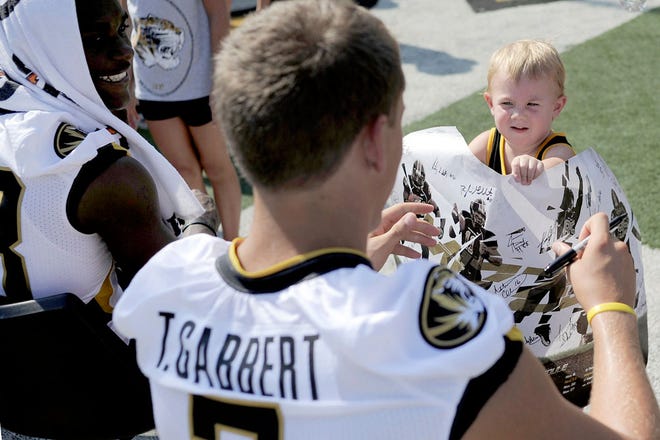 Addison Taylor, 2, gets freshman quarterback Tyler Gabbert to sign her poster at the fan event Sunday at Memorial Stadium. The Tigers’ season begins Sept. 4 against Illinois at the Edward Jones Dome in St. Louis.