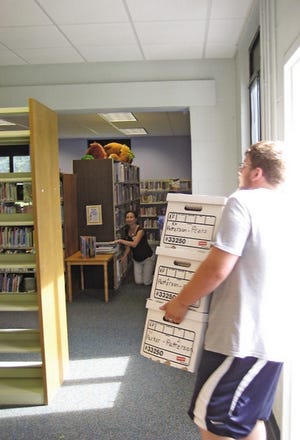 An Exeter High School football player helps bring books back into the Wiggin Memorial Library on Aug. 3. Books have been in storage as the library underwent renovations.
