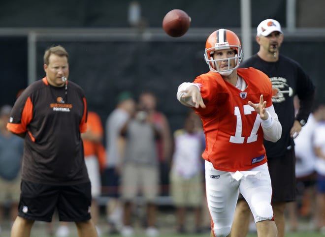 Cleveland Browns quarterback Jake Delhomme fires a pass as Head Coach Eric Mangini (left) watches during Tuesday’s training camp session in Berea.