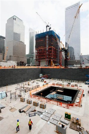 Construction continues on the National September 11 Memorial and Museum, below, Tuesday, Aug. 10, 2010, in New York. Construction cranes work above One World Trade Center, rear, also known as the Freedom Tower. (Mark Lennihan/ The Associated Press)