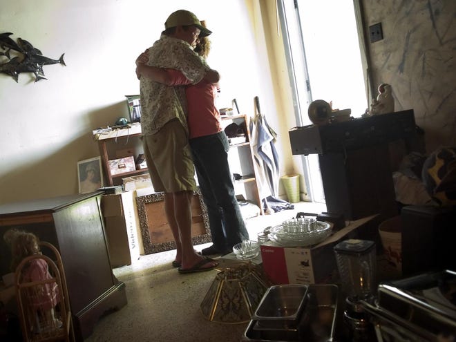 Teresa Beardsley falls into the arms of her husband, Donald, upon entering their Sarasota home of 30 years, which is being foreclosed upon. Most of their belongings, including heirlooms, are for sale after a move to a much smaller apartment.