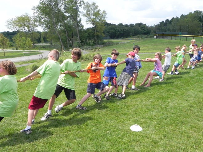 Children at the Parks and Recreation summer day camps participate in a tug-of-war at Burnt Hill Park last week. The town celebrated the park's one year anniversary by offering a variety of activities during the day for campers, and activities at night for families, including a jazz band performance.