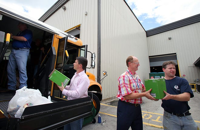 Hydro Aluminum employees, from left, Mark Merx, Dan Doherty and Brian Drysdale, load school supplies onto a St. Johns County school bus Friday afternoon.