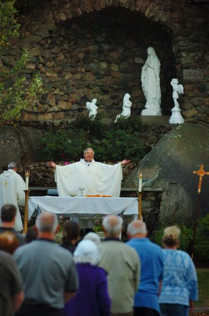 The Rev. Bill Salmon leads the rededication of the shrine at Immaculate Conception Church in Weymouth on Aug. 15, 2010. The desecrated shrine at Immaculate Conception was restored and was rededicated to 16 Weymouth men who died in World War II. The ceremony took place at an outdoor Mass at the Grotto of Our Lady of Lourdes on the parish grounds. A contingent of veterans and Mayor Sue Kay took part in the ceremony and Mass led by the Rev. Salmon. On May 16, parishioners discovered that the figure of Mary had been forcibly separated from the pedestal and toppled from the grotto. The statue broke into several pieces and the figure's head landed among plantings at the base of the shrine.