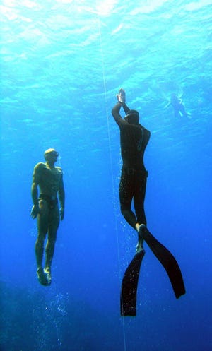 Sarasota diving instructor Mark Rush, pictured right, emerges from a 100-foot free-dive off the Cayman Islands in 2008. Other divers, to the left and at surface, are part of the buddy system - a safety measure taken because free-divers often black out or become disoriented when coming back up to the surface from deep dives.