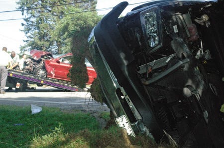 A man's black Chevrolet pickup truck is left on its side after a head-on collision with a red Ford Taurus on Route 1.