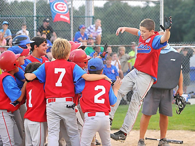 Members of the Phillies surround home plate as Josh Peters jumps in the air celebrating his grand slam in the sixth inning of Tuesday's Game 2 of the Taunton Little League city championship.