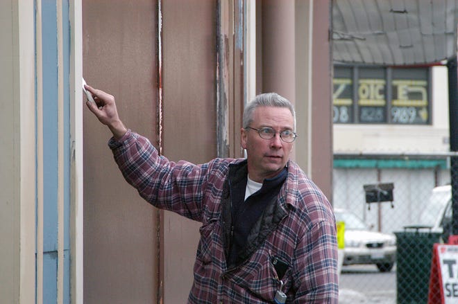 Mike O'Donnell scraping graffiti, which he allegedly scrawled on the side of the Star Theater building.