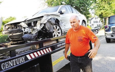 Ralph Cresta, owner of National Wrecker Service, prepares a vehicle for transport following a crash with another car on State Road in Eliot, Maine on July 7, 2010.
