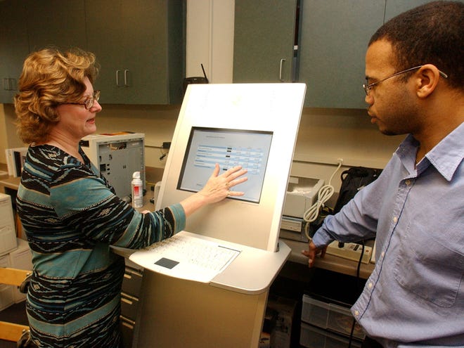 Nancy Pack, left, director of the Tuscaloosa Public Library, and Kevin Smith make a trial run throeugh a survey on the library survey kiosk at the library in this 2005 file photo. Pack, the library's director since 1999, resigned from her position last week.