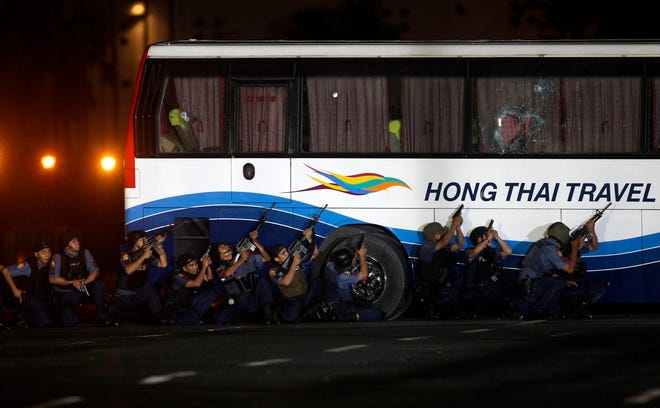 Police and SWAT members take positions outside a tourist bus in an attempt 
to rescue hostages Monday at Rizal Park in Manila, Philippines. An armed man 
had seized the bus with 25 people aboard.ASSOCIATED PRESS
