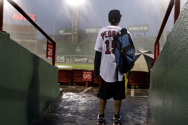 A young Red Sox fan looks out at the field at Fenway Park last night. The rain forced the postponement of the game until today, when Boston and Seattle will play a day-night doubleheader.