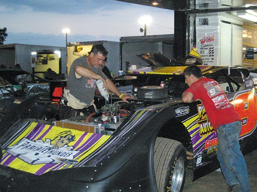 Eric Smith of Shirley, left, the 2010 UMP late model track champion at Fairbury American Legion Speedway, primes his stock car’s carburetor with fuel prior to starting the engine before Saturday night’s racing during the Fairbury Fair, while a crew member looks on. Smith was the 2009 track champion in the late model division at Farmer City Speedway, and while he has come in second in points at Fairbury in 2004 and 2005, this is his first time atop the standings at Fairbury.