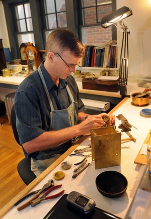 Richard Hills, owner of Hills Antique Clock Shop in Holliston, works in his workshop yesterday.