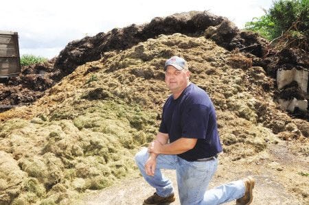 Allen Smith of Great Bay Farm in Newington, poses near a huge pile of grass clippings and old leaves that community members have dropped off at the farm. Smith says they need to stop letting people dump them there due to the heavy volume and the inabiltiy to keep up with composting it. People will be able to drop off through the fall however.