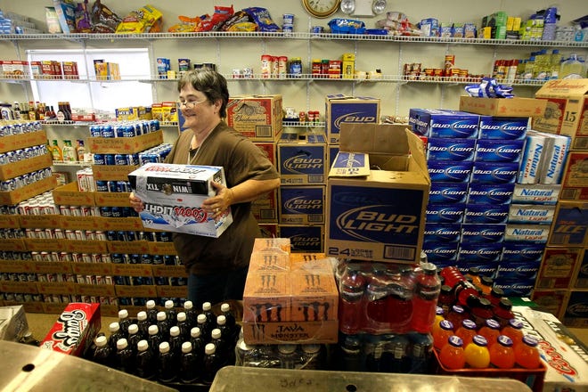 Convenience store owner Sharon Couture stocks cases of beer in Sharon's Discount Store in Yscloskey, La., Thursday. Couture's business, which served local commercial and recreational fishermen before the Deepwater Horizon oil spill, has remained mostly intact thanks to contract workers from nearby 
spill response bases.