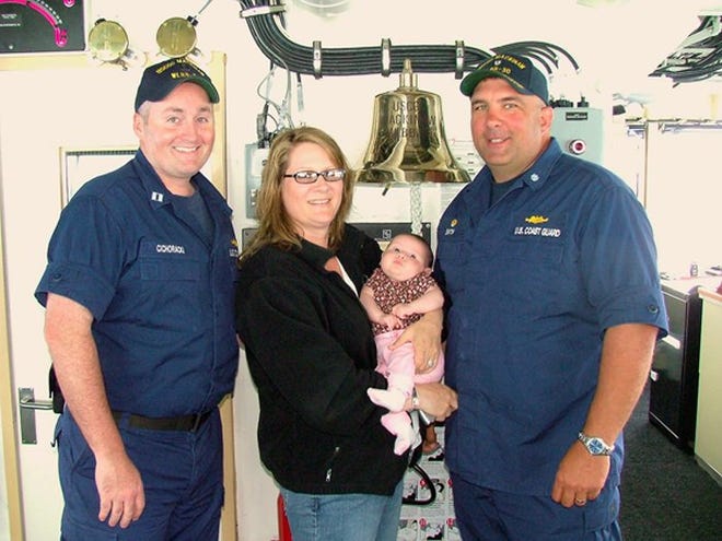 The first baby baptized in the ship’s bell of the new U.S. Coast Guard cutter Mackinaw is Isabella Lynne Chichoracki, daughter of Corey and Margaret Chichoracki. The family posed with Cmdr. Scott Smith (right) in front of the bell aboard the Mackinaw.
