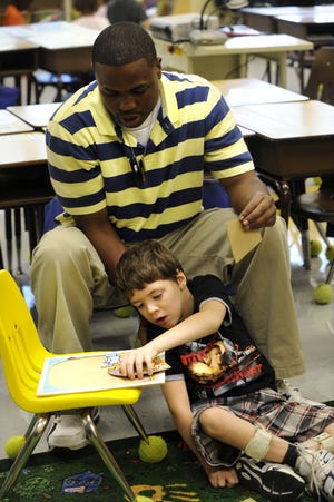Class Assistant Jason Culler helps Zack Heisler, 7, a first grader at McGregor Elementary School in Canton.