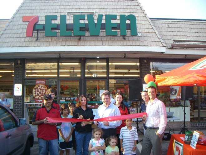 Franchise owner Gail Bagnera, center with scissors, cuts the ribbon to celebrate the grand opening of the 7-Eleven store on Hamilton Street.