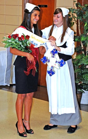 Madison “Maddie” Bahry receives assistance from 2009 Evangeline Margaret Beatty, right, placing the banner and taking the crown as the 2010 Evangeline, Queen of the International Acadian Festival.