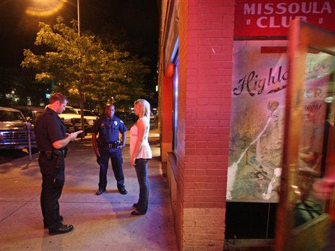 In this photo taken Aug. 20, 2010, Missoula police officers check the I.D. of a woman outside the Missoula Club bar in Missoula, Mont. Montana has long been a state where you could crack open a beer and drive down the interstate just about as fast as you liked. Drinking and driving was legal until 2003, when it was changed only under heavy federal duress, and there was no specified speed limit on major highways.  But spurred by the high-profile death last year of a highway patrolman at the hands of an intoxicated driver, Montana's Old West drinking and driving culture is in retreat.  (Mike Albans/ The Associated Press)