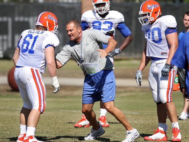 Florida defensive line coach Dan McCarney, center, goes through defensive plays with offensive lineman Gary Beemer, left, defensive end Kedric Johnson, center back, and offensive lineman Shawn Schmieder, right, during football practice at Sanders Practice Fields on Saturday, March 20, 2010.
