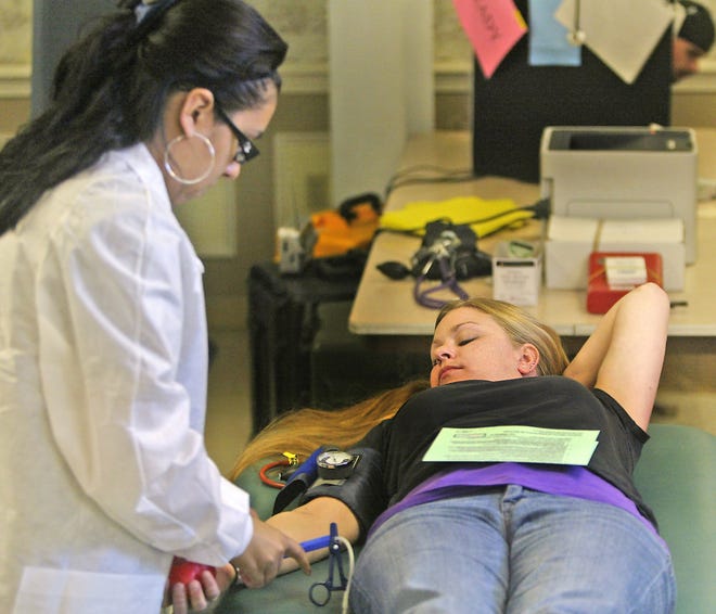 Nicole Vischer, of Norwood a regular blood giver, gets ready to give blood assisted by Red Cross worker Ana Lopez.