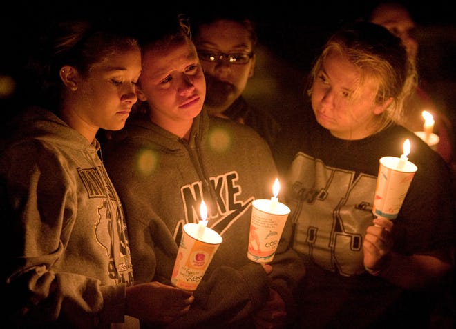 Cheyenne Malcolm, center, a ROWVA High School sophomore, is comforted by her sister Haley Faull, left, and friend Kayla Morehead, right, a former ROWVA student and now a senior at Galesburg High School, during Wednesday night's candlelight vigil at Bill Adams Field at ROWVA High School in Oneida.