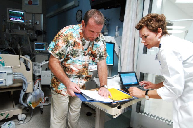 Dr. Beth NeSmith (right) checks a patient's chart with registered nurse Eric Gill at Medical College of Georgia Hospital and Clinics. She is researching whether stress makes trauma patients more likely to have complications.