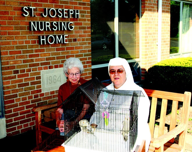 Sister Agnes Stetson and resident Marion Brummitt look at a pet bird at St. Joseph Nursing Home. Brummitt was a volunteer at St. Joseph for 27 years before she moved there.