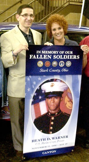 Scott and Melissa Warner hold a banner of their son, Marine Corps Private Heath D. Warner.