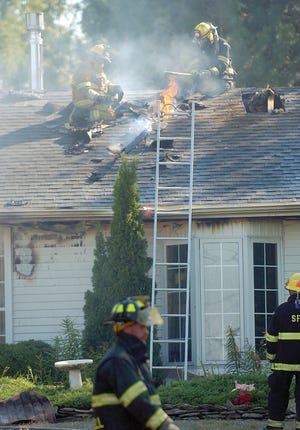 Firefighters ventilate the roof of a home located at 3953 Dewey Road in Shortsville, during a structure fire on Tuesday, September 7, 2010.