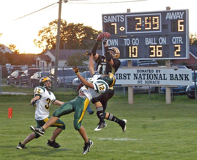 St. Ignace’s Austin St. Louis (11) hauls in a 37-yard TD pass from Cole Christiansen while being defended by Derek Vongphasouk (12) and Travis Riedel. St. Louis had 118 yards receiving and 100 yards rushing and scored three TDs.