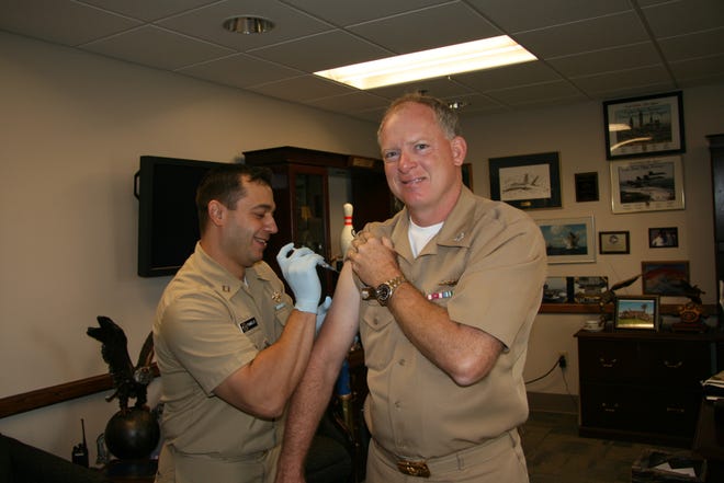 Naval Station Mayport Commanding Officer, Capt. Aaron Bowman, receives a flu shot from Lt. Hristos Tsingelis, the preventive medicine officer at Naval Branch Health Clinic Mayport. Service members are required to receive flu shots annually.