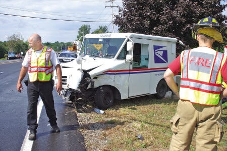 Greenland Fire Chief Ralph Cresta, left, and firefighter Rob Holt investigate the scene of a two-vehicle crash involving a U.S. mail delivery truck on Route 33, at the Intersection of Route 151 in Greenland on Tuesday. The mail truck crashed into the control box for the traffic signals, causing delays.