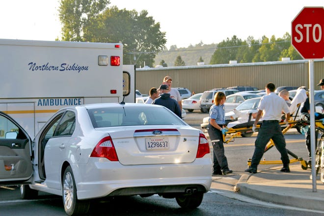 Medical and fire personnel roll an 8-year-old boy into a Northern Siskiyou Ambulance at the corner of Lawrence Lane and South Oregon Street on Tuesday morning after the boy was struck on his bike by the woman driving the Ford Fusion 
pictured at left. The boy received minor injuries, including 
abrasions to his wrists and ankles.