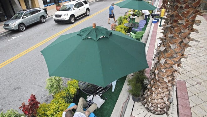 Josh Nichols, Sustainability Program Coordinator for West Palm Beach, tries out one of the chairs as workers set up plants and furniture in parking spots on Clematis Street in front of the city library for national PARK(ing) Day.