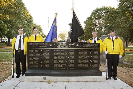 Larry Purtzenski, Dave Heimerdinger, Dave Matzinger and John Schuler from Clinton AMVETS Post 176 stand near the Vietnam Memorial in Adrian’s Monument Park.