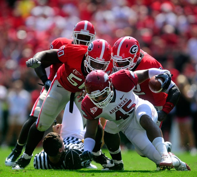 Arkansas tight end D.J. Williams (45) runs over a referee and Georgia defenders Darryl Gamble (50) and Justin Houston (42) on a gain in the first quarter of the University of Georgia football game with Arkansas at Sanford Stadium in Athens, Ga. on Saturday Sept. 18, 2010.  (David Manning/Staff/david.manning@onlineathens.com)