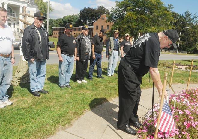 Leslie Spousta, right, places the second flag at the Vietnam fountain on Church Green at the beginning of the 24 hour vigilremembering POW-MIAs.