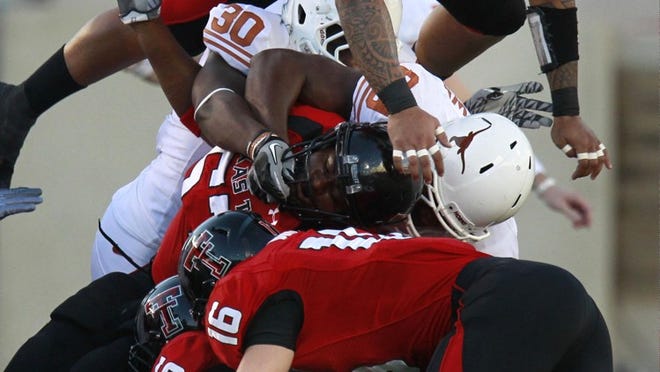 Texas running back Cody Johnson (bottom) is stopped for a 1-yard gain by several Texas Tech defenders to stop an early drive Saturday night in Lubbock.