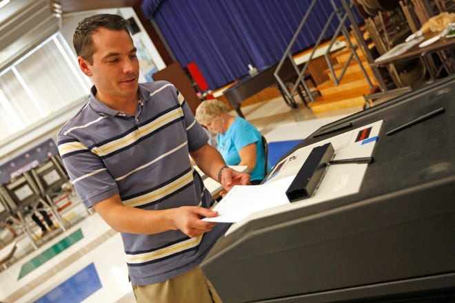 Michael Hilston turns in his ballot after voting in Tuesday's primary election.