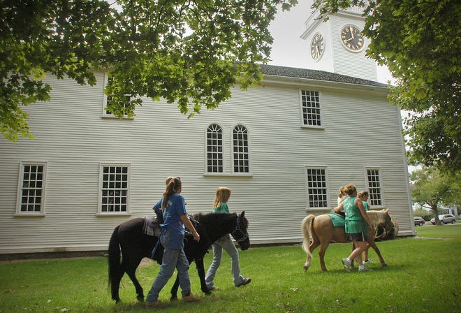 Marshfield resident Cheryl Mechan, left, and helpers give pony rides on Cohasset Common during a recent farmers’ market.
