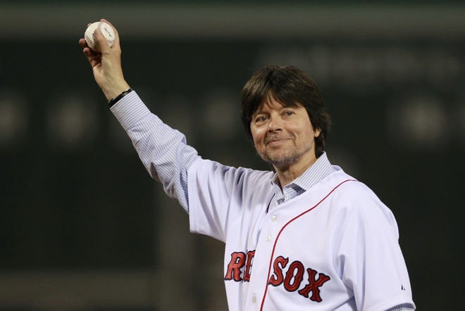 Filmmaker Ken Burns holds up a baseball before delivering a ceremonial first pitch prior to a Boston Red Sox game at Fenway Park in Boston on Tuesday, Sept. 21, 2010.