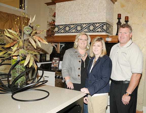 Owners Amie Pelham and Craig Barnes with general manager Lisa Van Sickle, center, pose in their new showroom at Classic Cabinets and Interiors LLC in Adrian.