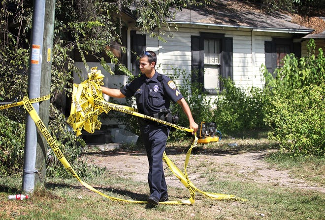 Cpl. Robert Fanelli removes crime scene tape from the scene of one of Monday's shootings.